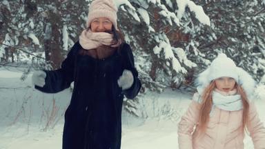 快乐妈妈女儿跳舞冬天树背景降雪